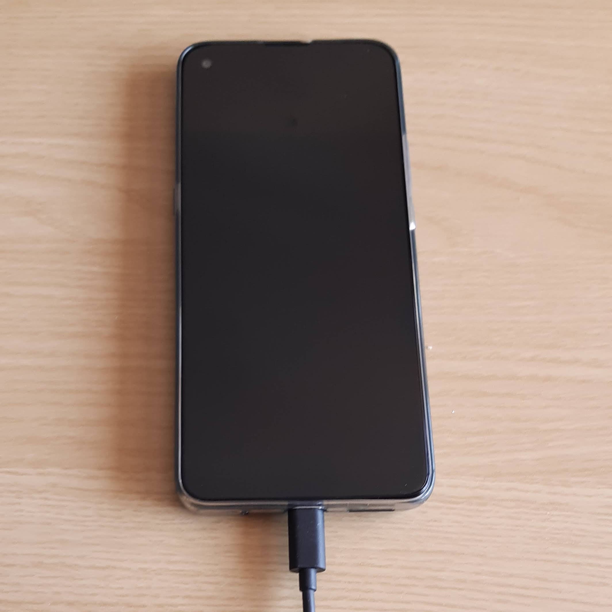 A smartphone with charging cable plugged in on a table